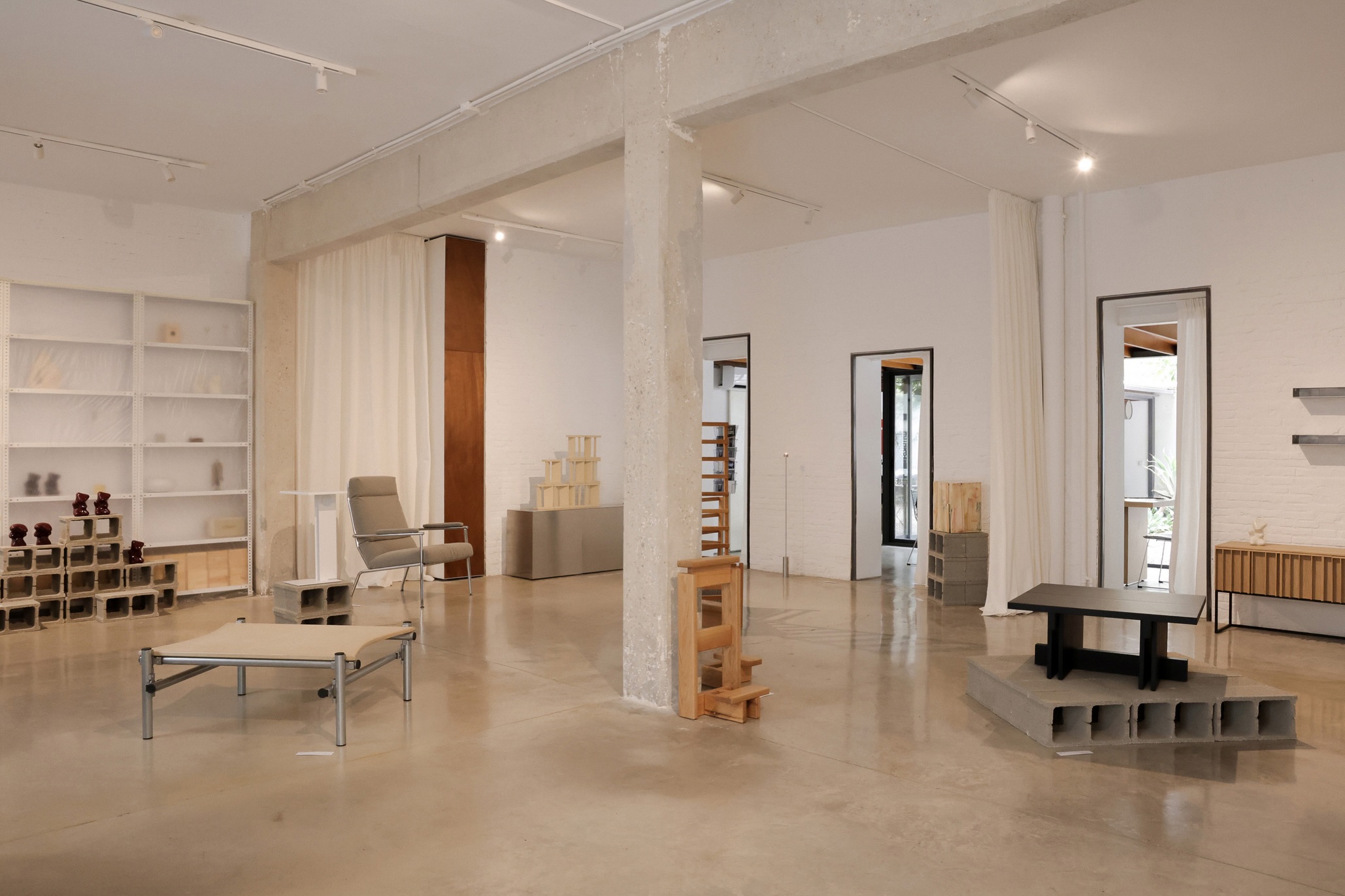 Sala de Fondovisto con piezas de diseño sobre bloques de hormigón, columna central y paredes de ladrillo blanco