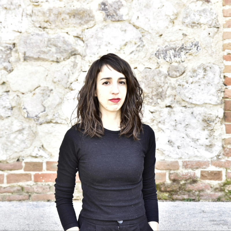 Retrato de la escritora Layla Martínez ante un muro de piedra y ladrillo