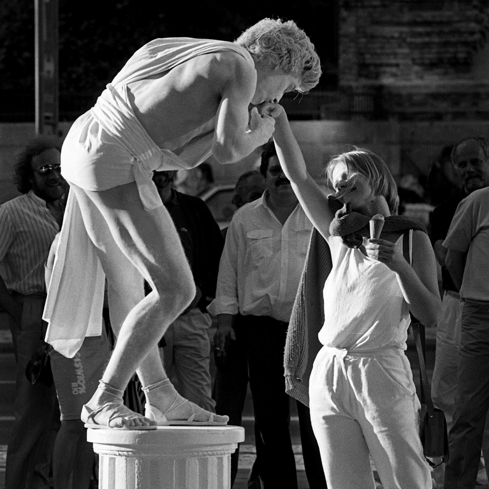 Una bailarina subida a un cubo recibe el beso de una niña, fotografía callejera en blanco y negro de David Hornback
