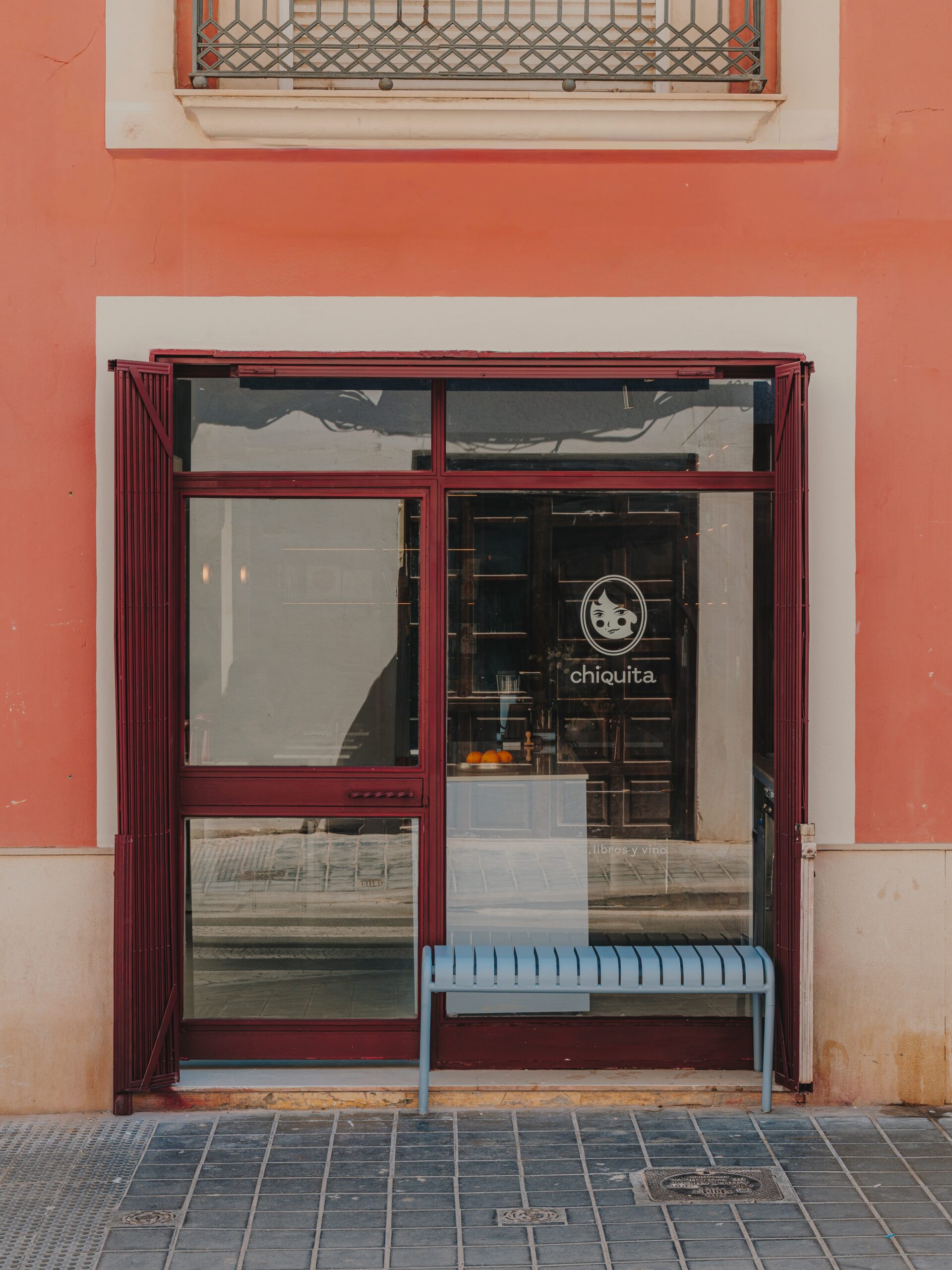 Fachada de Chiquita en Borrull, con puerta burdeos y banco azul