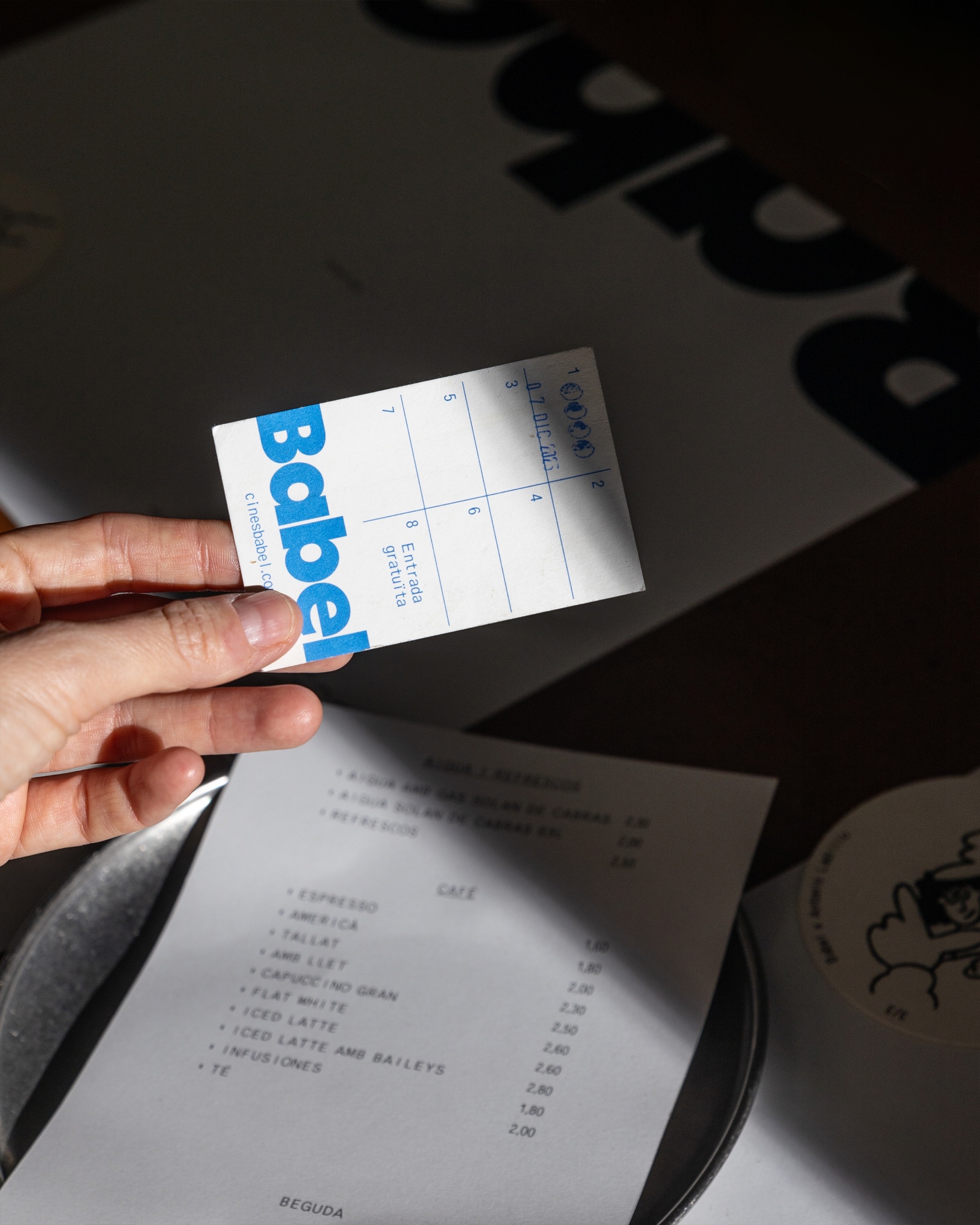 Tarjeta de los Cines Babel con el logotipo azul junto a la carta del bar